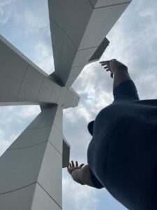 Traveler standing beneath the cross structure of St. Paul’s Cathedral in Abidjan, arms raised upward