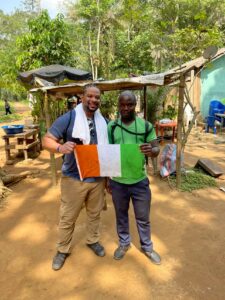 Traveler and local guide standing together in Banco National Park, Abidjan, holding the Ivorian flag