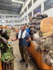 Traveler walking through an indoor market in Abidjan lined with herbs, pottery, and traditional goods